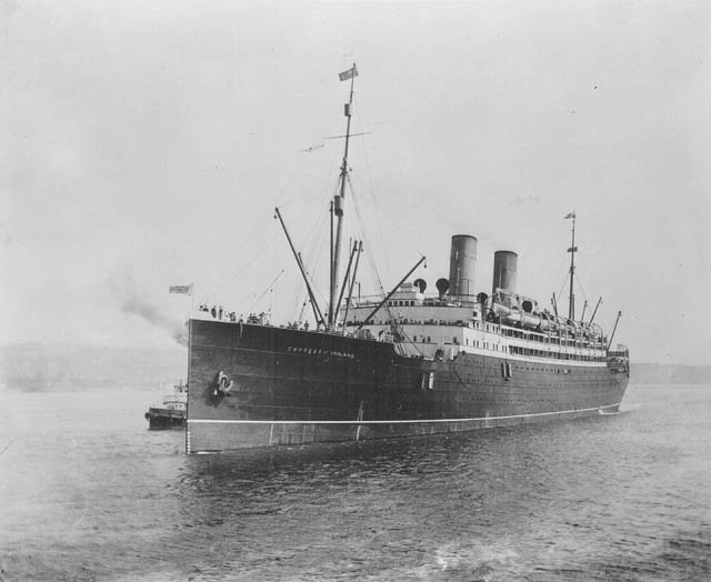 Black and White Photograph of the S.S. Empress of Ireland. The ship has 2 chimneys. Passengers can be seen on the foredeck. The Union Jack is displayed on the bow of the ship.