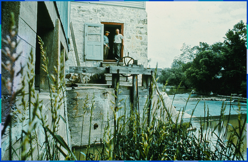 The photo shows the western side of the mill and has been taken from the water level. Donat and Philippe Légaré are standing at the top of the stairs leading to the water gate.