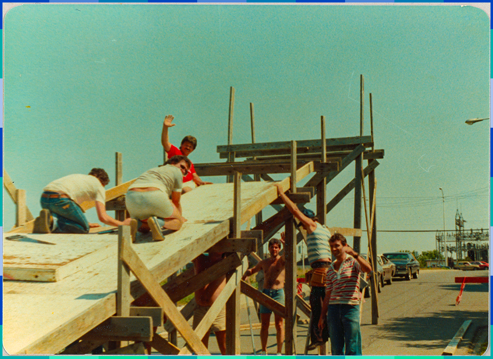 Six men from the Optimist Club greet the camera during the construction of the wooden ramp, which is around three metres high.