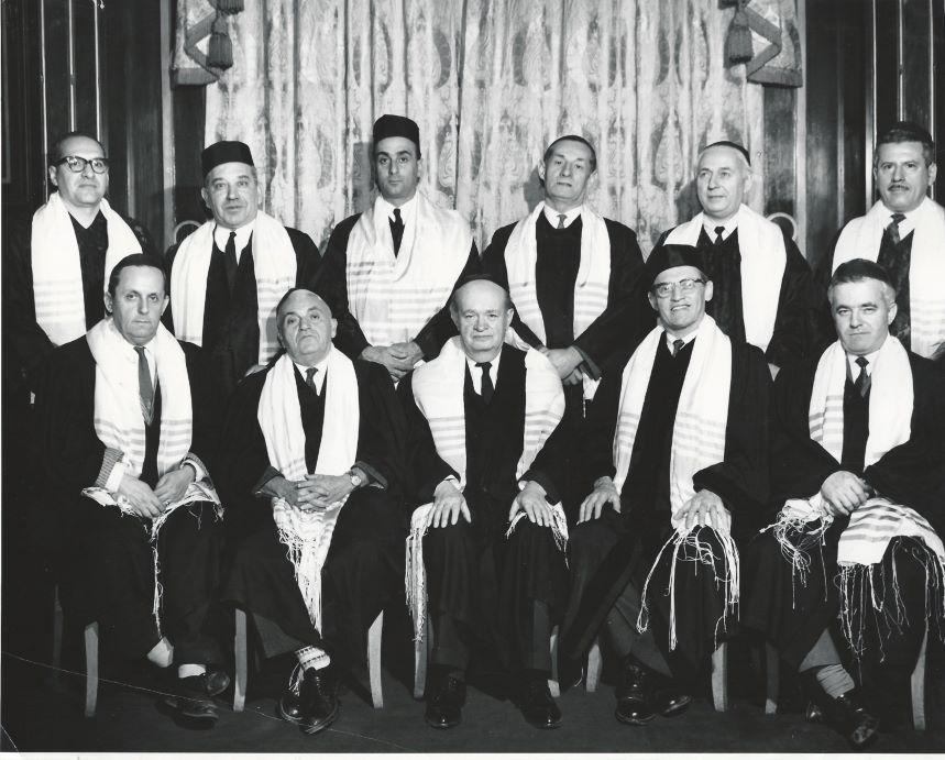 Black-and-white photograph of a group of men wearing black robes and white prayer shawls.