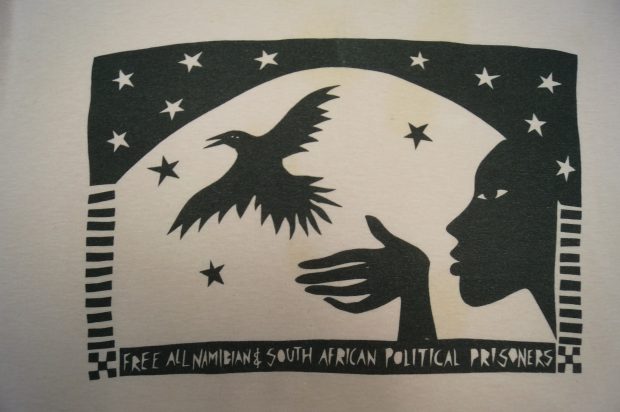 A blanket which states Free All Namibian and South African Political Prisoners with a woman letting go of a bird.