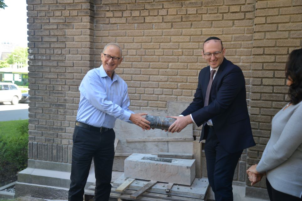 Two men retrieving a time capsule from a synagogue cornerstone.