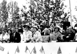 Black and white photograph of several rows of seated dignitaries watching celebrations which are out of the field of view.