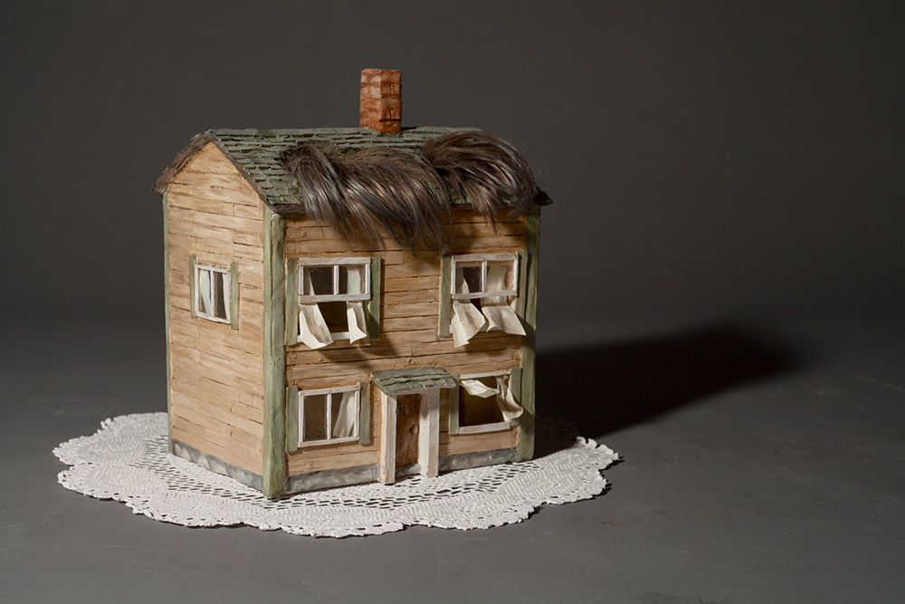 Sculpture of a house with a fringe of hair