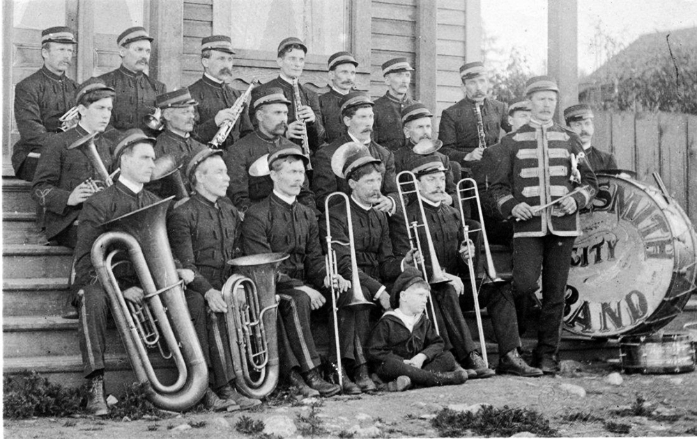 Black and white photograph of twenty uniformed band members holding their brass and wind instruments.