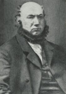 A 19th century man with a chinstrap beard, and wearing a suit. Marcus Ollendorf