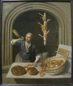 Framed oil painting: baker in his shop. Man with a cap blowing a horn. Light counter: round brown loaves, pretzels, wicker basket, pastries. Behind: pretzel display. Dark background. Warm, artisanal atmosphere.