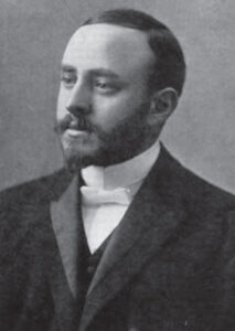 A black-and-white early 20th century photograph of a man with a short-trimmed beard, wearing a suit. Rabbi Herman Abramowitz.