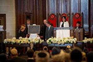 A group of people standing at a podium in a synagogue, unveiling a plaque.