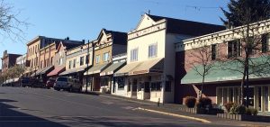 Colour photograph of one side of a town street lined with two and three story early 20th century buildings of varied heritage character. Many have canvas awnings over their ground floor shopfronts.