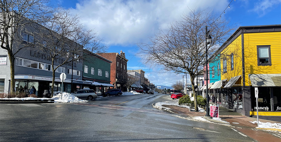 Colour photograph looking down a commercial steet with a variety of heritage buildings on either side, some with colourfully painted wooden siding, some grey stucco and others red brick.