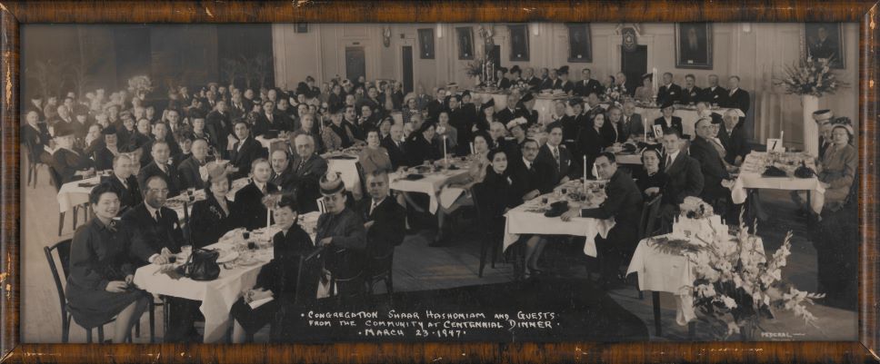 Black-and-white photograph of a crowd of people sitting at tables for a dinner.