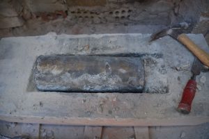 A brass cylinder time capsule embedded in a piece of stone.