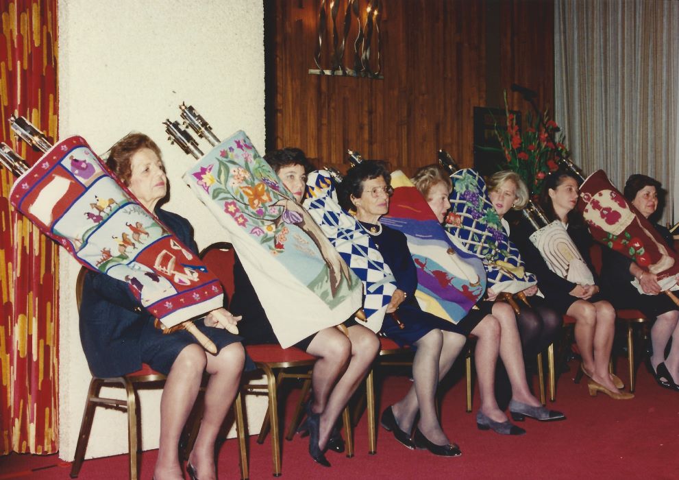 A group of women sitting in chairs, holding Torah scrolls.