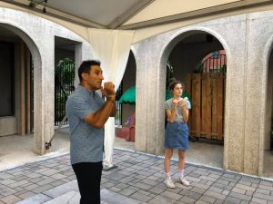 A man teaches a teenager how to hold and blow a shofar.