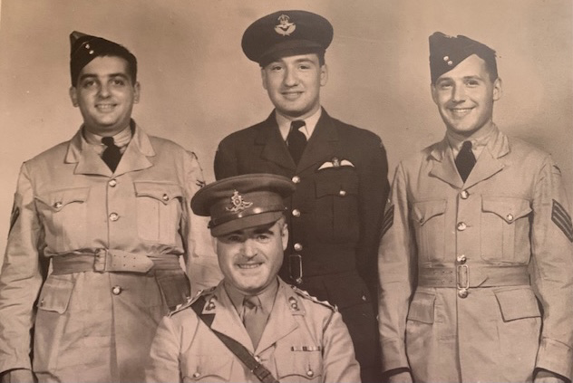 A group of four men World War I and World War II military uniforms.