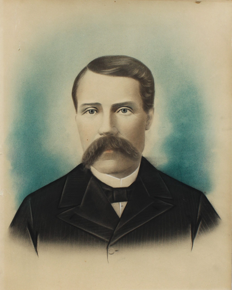 Hand-colored portrait of a man with neatly parted dark hair and a large, bushy mustache. He wears a dark suit with a high-collared white shirt and a bow tie. The background features soft shades of teal fading into cream, giving the portrait a vintage, studio-painted appearance.