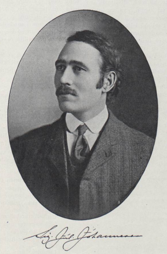 An oval black and white portrait photo of man from the shoulders up. He has dark hair combed to the side with sideburns and a mustache. He is looking to the left wearing a suit and tie. Below the photo, his cursive signature is printed.