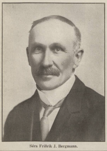 Black-and-white portrait of a man shown from the shoulders up. He has a neatly combed hairstyle, a trimmed mustache, and wears a formal jacket with a high-collared shirt and tie. His name, Séra Friðrik J. Bergmann, is printed below the image.